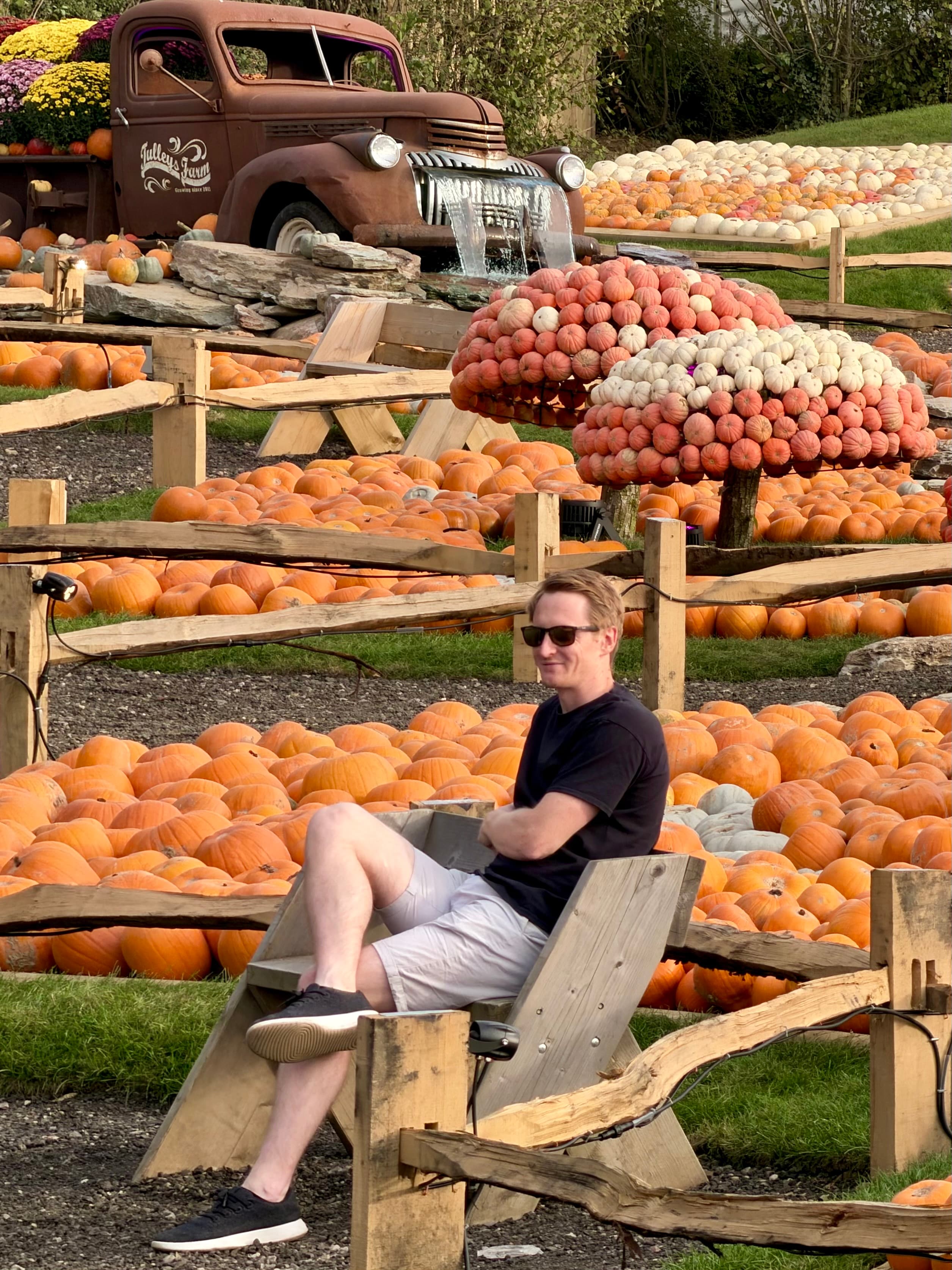 On a bench in front of the pumpkin toadstools and the rusty truck