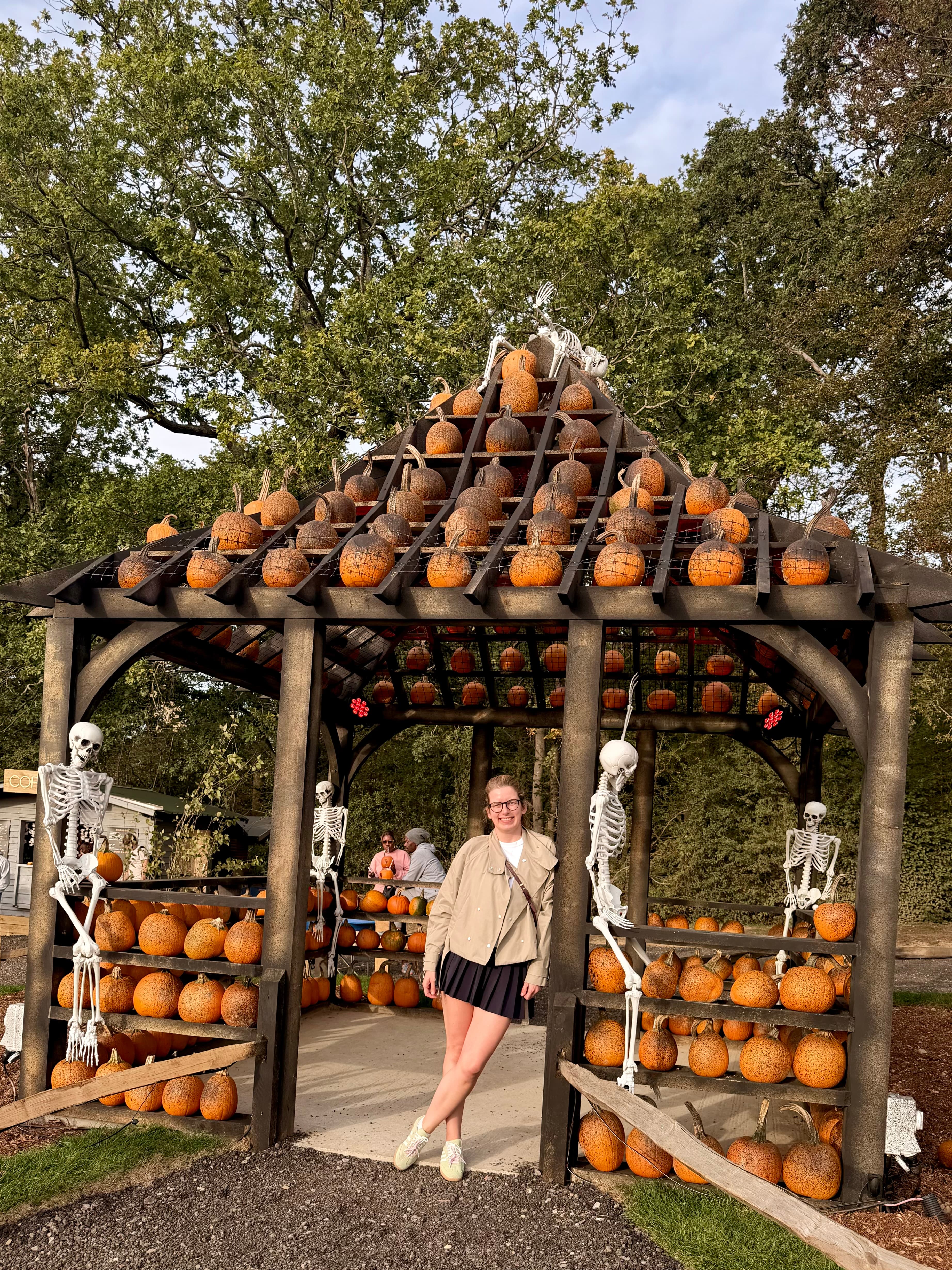 A gazebo with pumpkins on the roof and skeletons at the posts